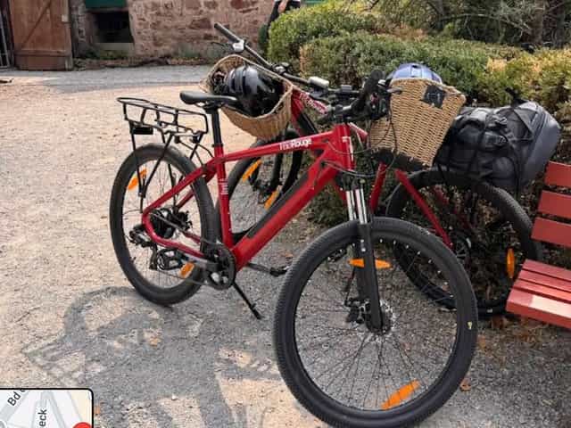 Deux vélos électriques rouges VeloRouge garés dans une cour alsacienne