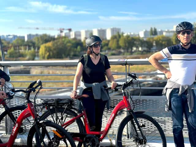Two riders with red electric bikes by the water
