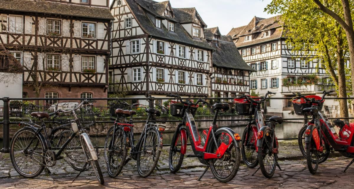 City bikes and red electric bikes lined up along a cobbled quay in Petite France, Strasbourg