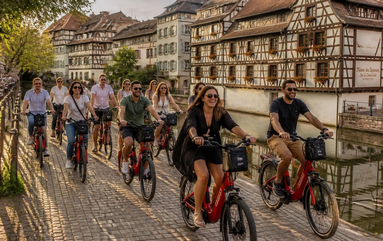 A group of riders on red VéloRouge e-bikes along the canal in Petite France, Strasbourg